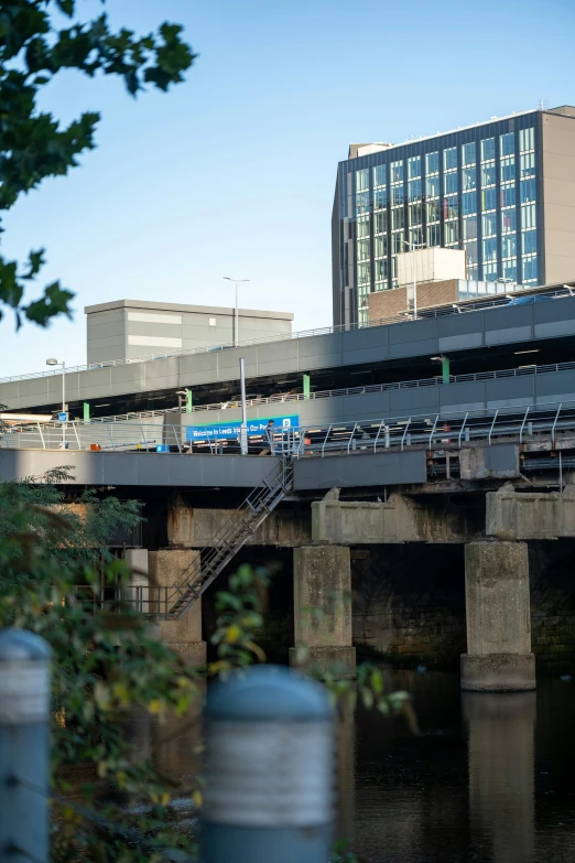 some stairs are near a bridge with a blue train coming from it