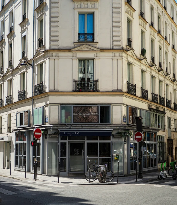 a two story white building is on the corner of a street with a sign reading welcome to paris