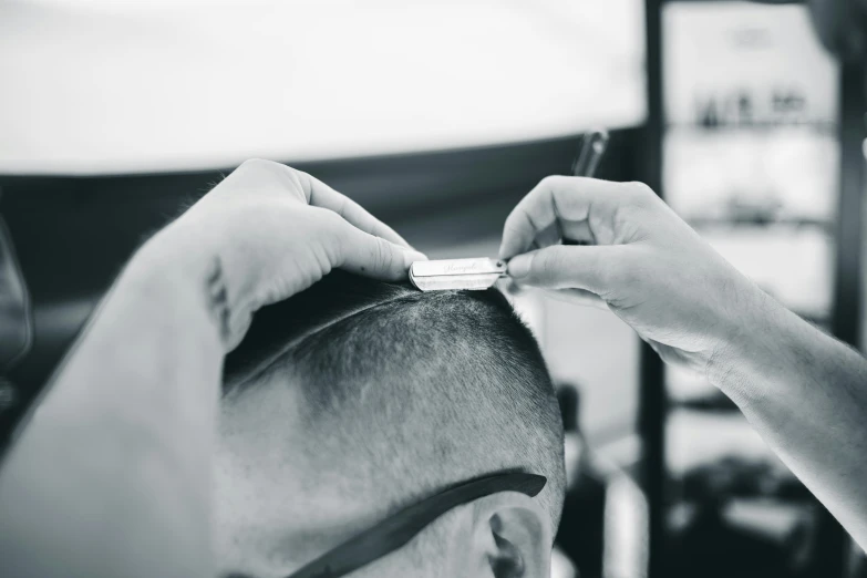 black and white pograph of man in barber shop  another mans hair