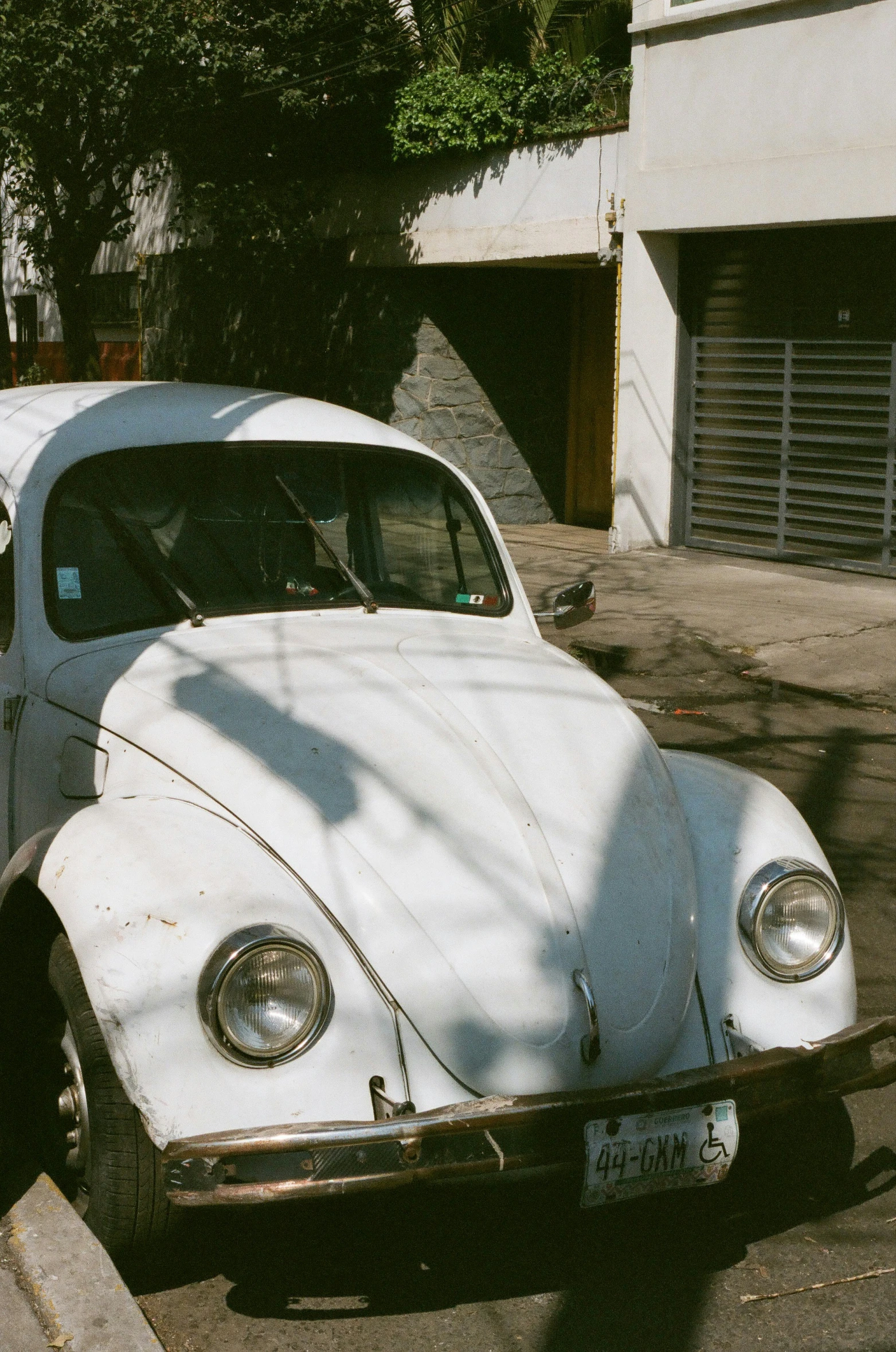 an old white beetle sitting in a parking lot