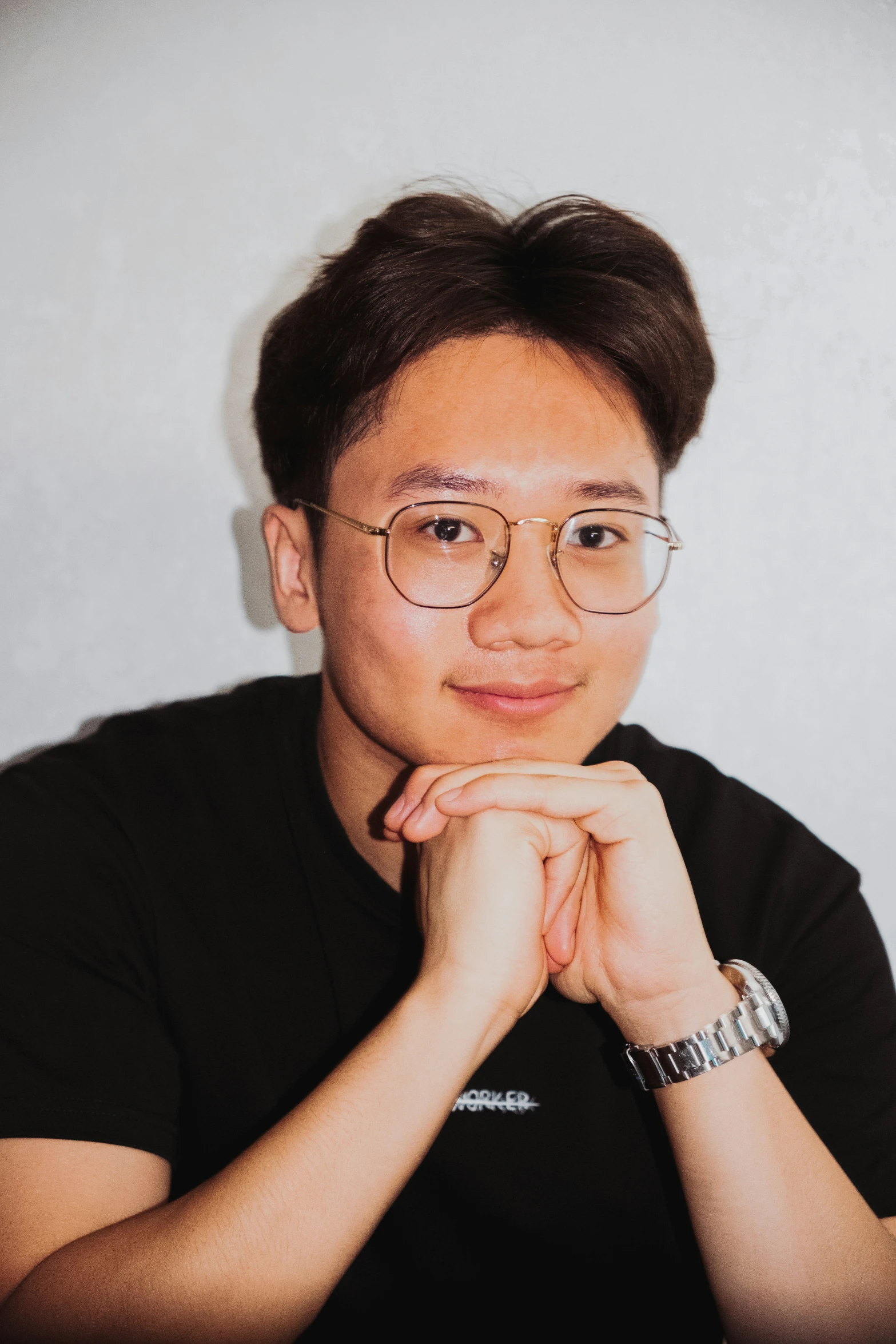 a man with glasses sitting against a wall