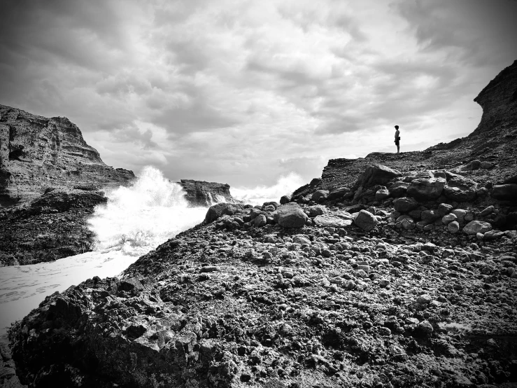 a person standing on top of a rocky shore next to water