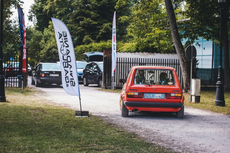 a red car that is driving down a street