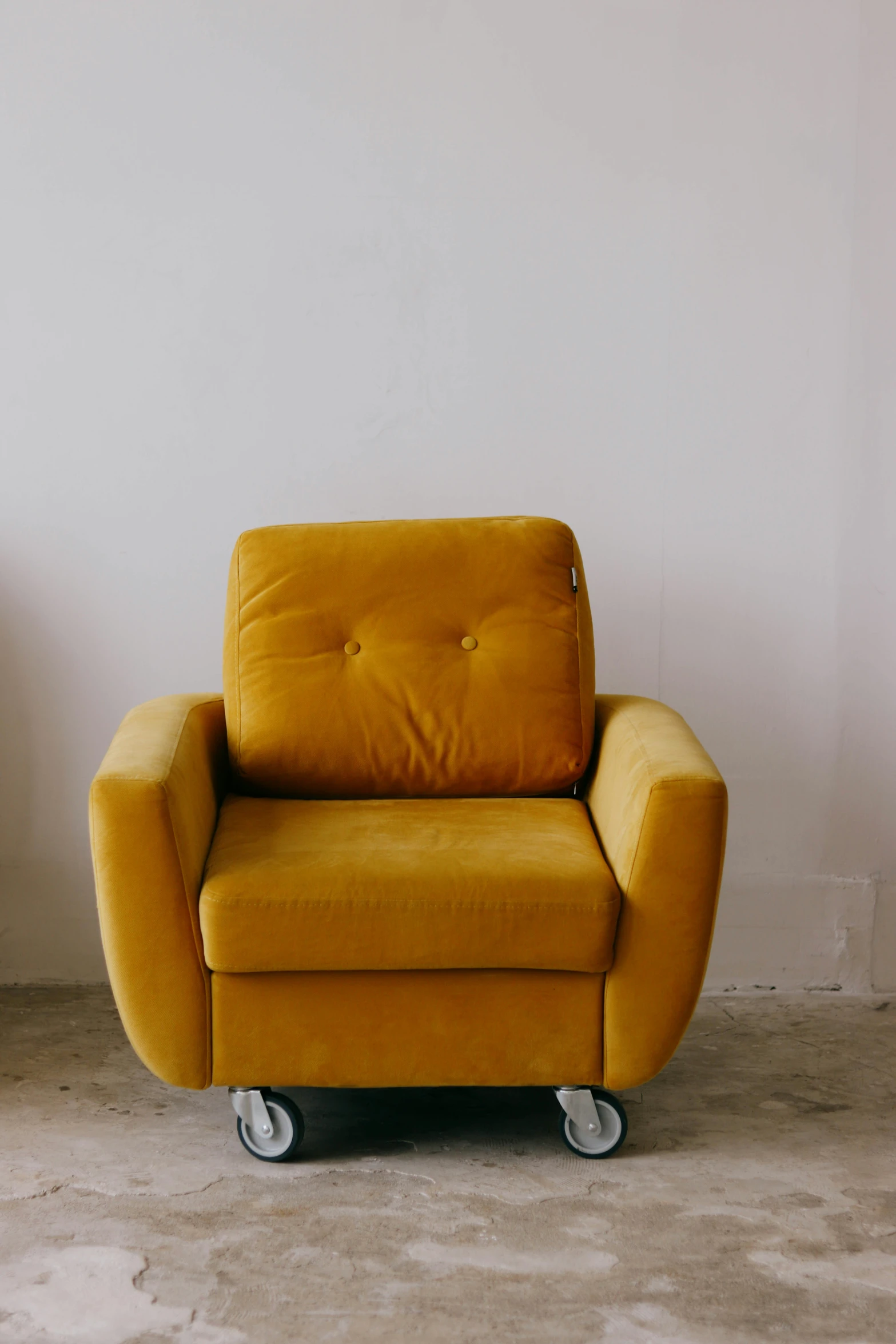 an empty yellow chair against a white wall