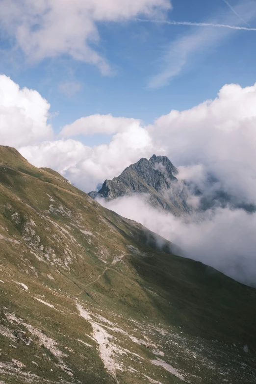 a mountain that has some clouds flying over it