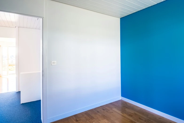 the blue wall is painted white and features a white wooden floor