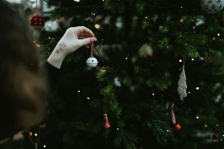 a woman's hand holding an ornament on a christmas tree