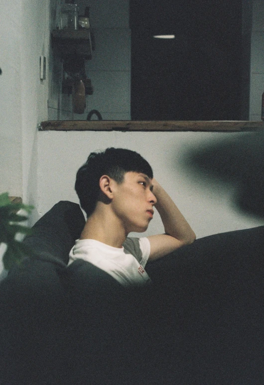 a young man sitting on top of a sofa in a room