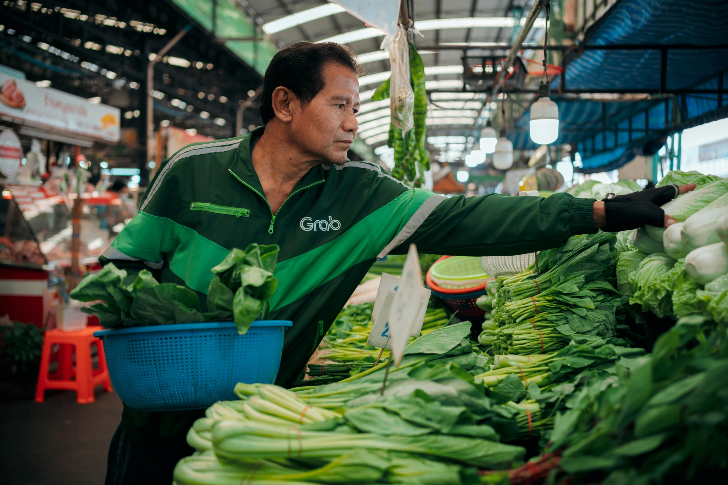 a man holds up a bucket full of green vegetables