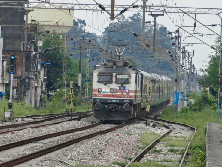 a train traveling past many tall buildings with power lines above