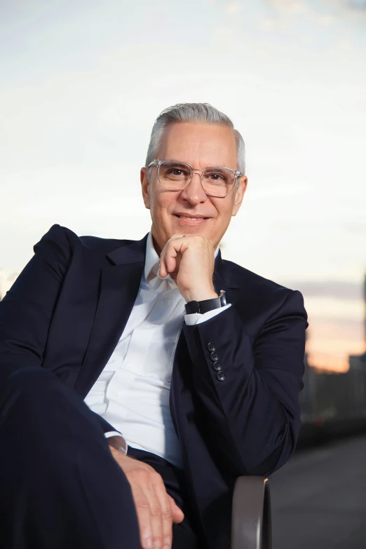 an older man sitting on a chair posing for a picture