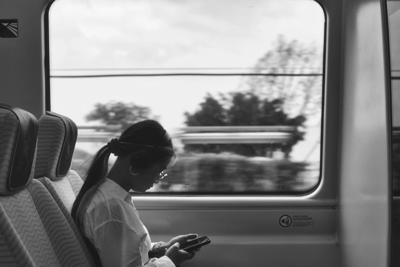 a woman sitting on a bus and using a cell phone