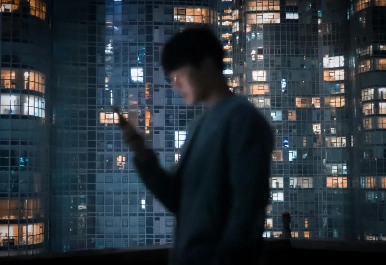 a person standing with their cell phone in front of a cityscape