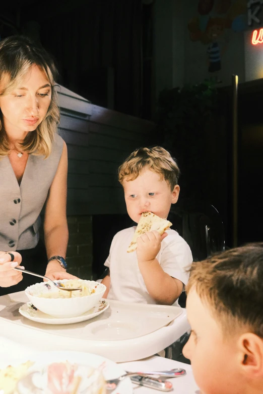 the mother and two s are eating dinner together