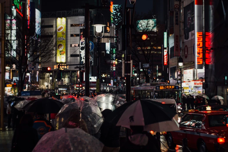 people on a rainy night holding umbrellas and walking