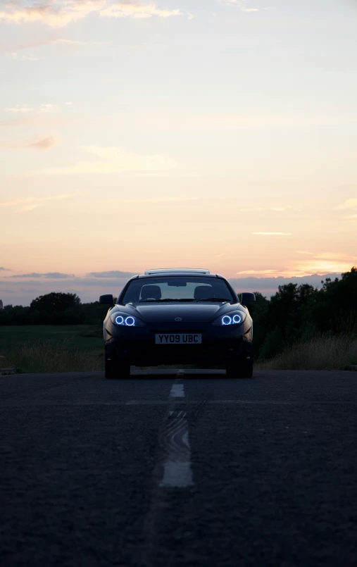 car driving down the road in front of a sunset