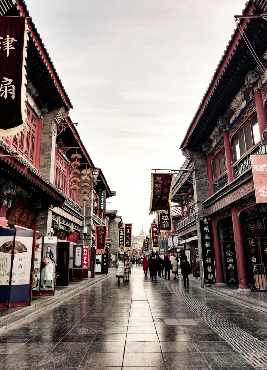 a city street has a wet sidewalk in front of chinese buildings