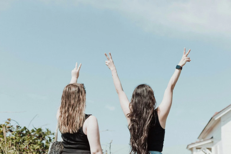 two girls standing next to each other in front of some clouds