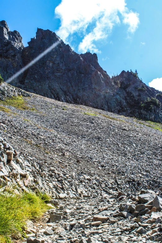 rocks and grass in front of a mountain under a partly cloudy blue sky