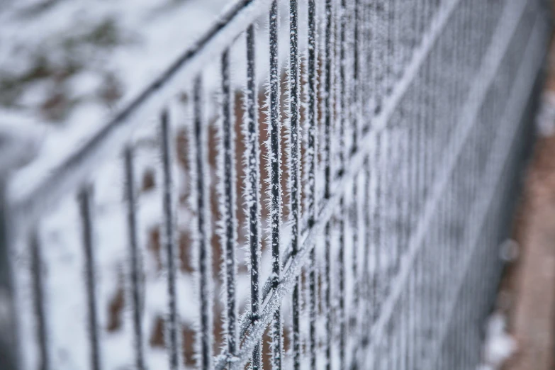 a fence with snow falling on the top