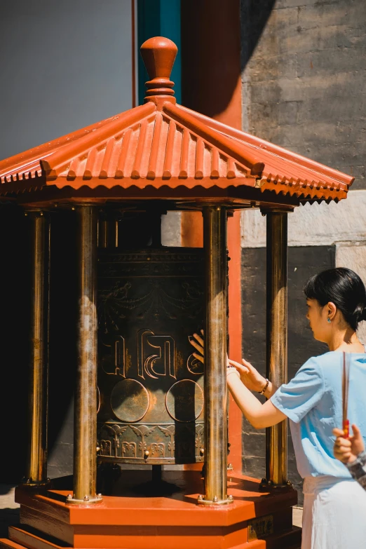 a woman is playing with the hand - painted decoration on the shrine