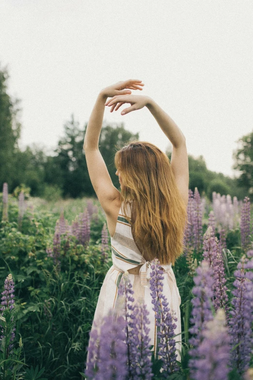 a woman standing in purple flowers doing yoga