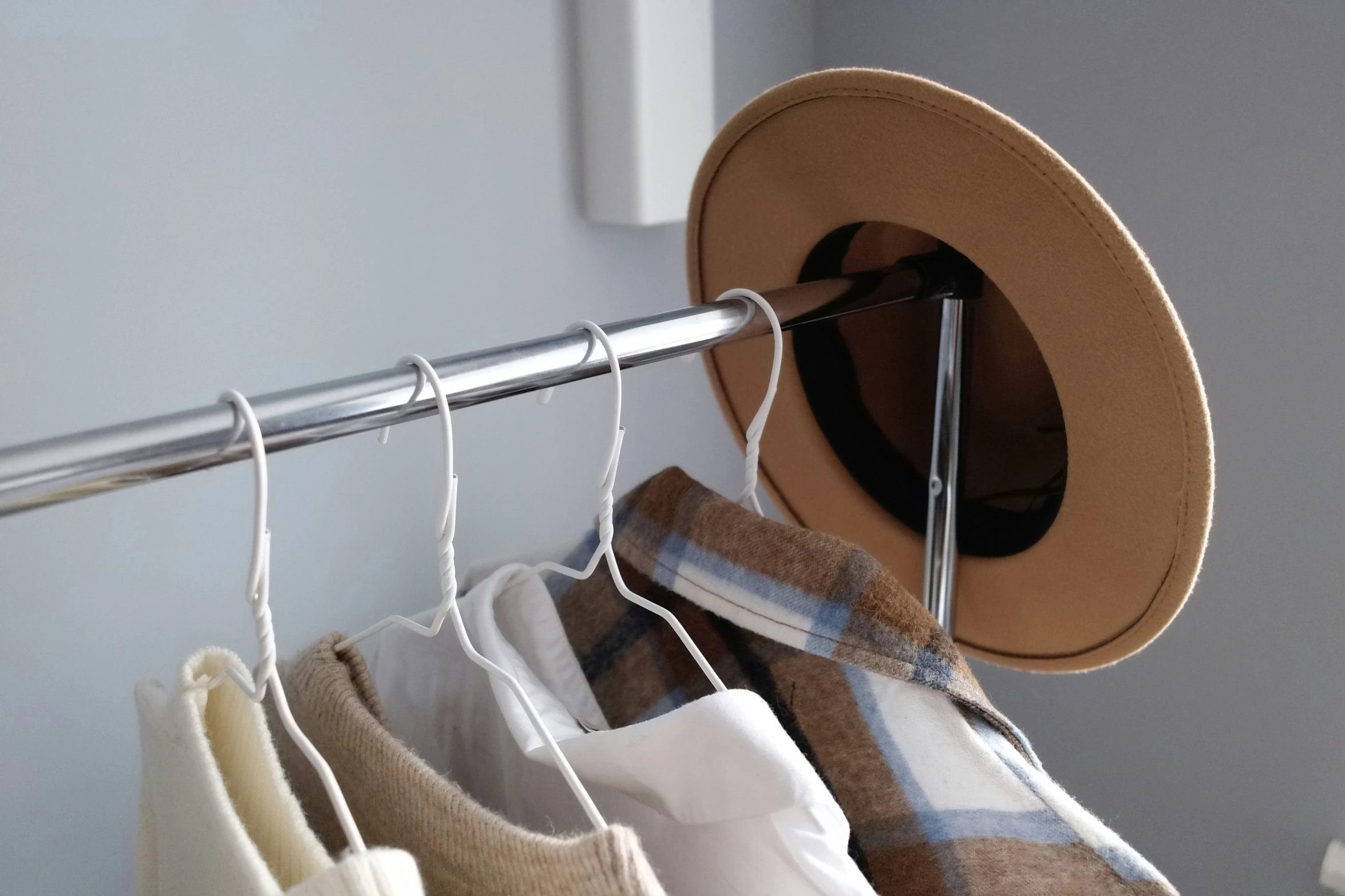 clothes hang on a metal rail by a hat