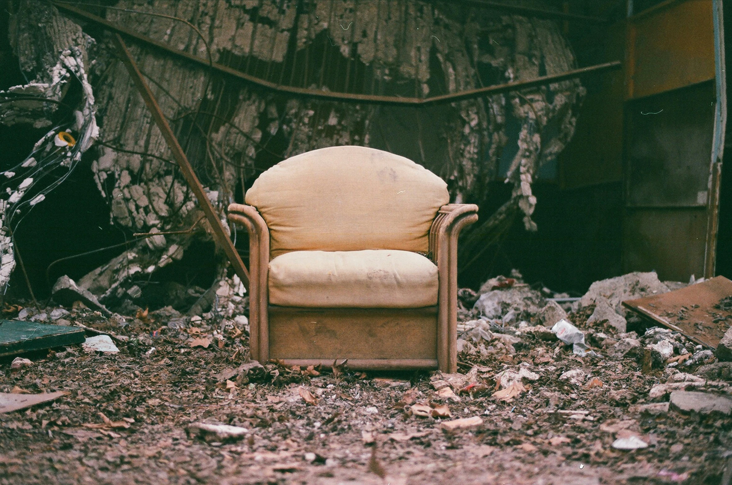 an old brown chair sitting on the ground next to a pile of rubble