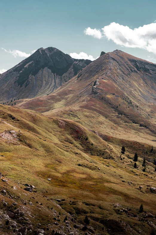 a large mountain sitting behind two green mountains