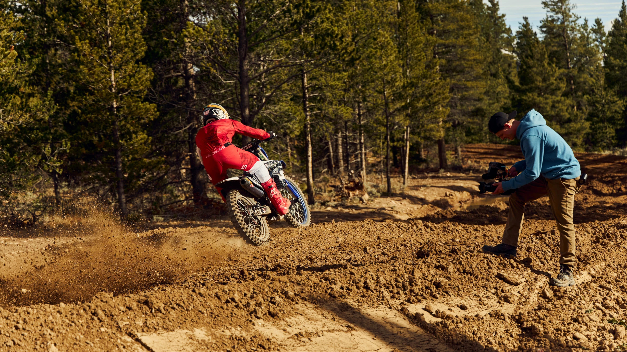 two people riding motorcycles through the mud on a track