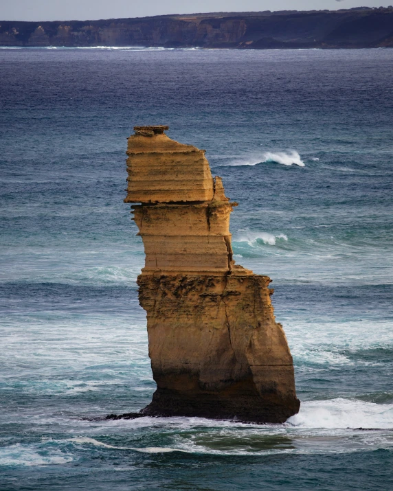 a rock outcropping in the ocean has some waves crashing