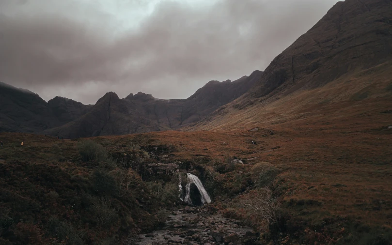 a waterfall flowing down a mountain side next to grass