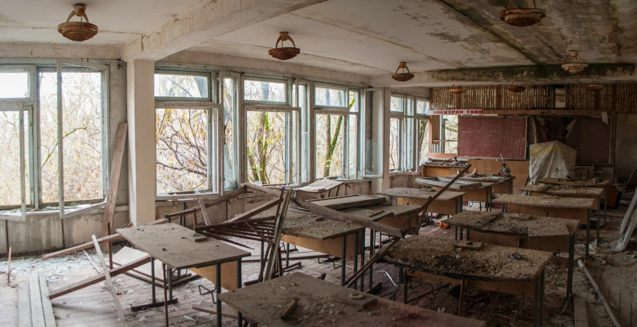 a room full of desks and a chair in front of large windows