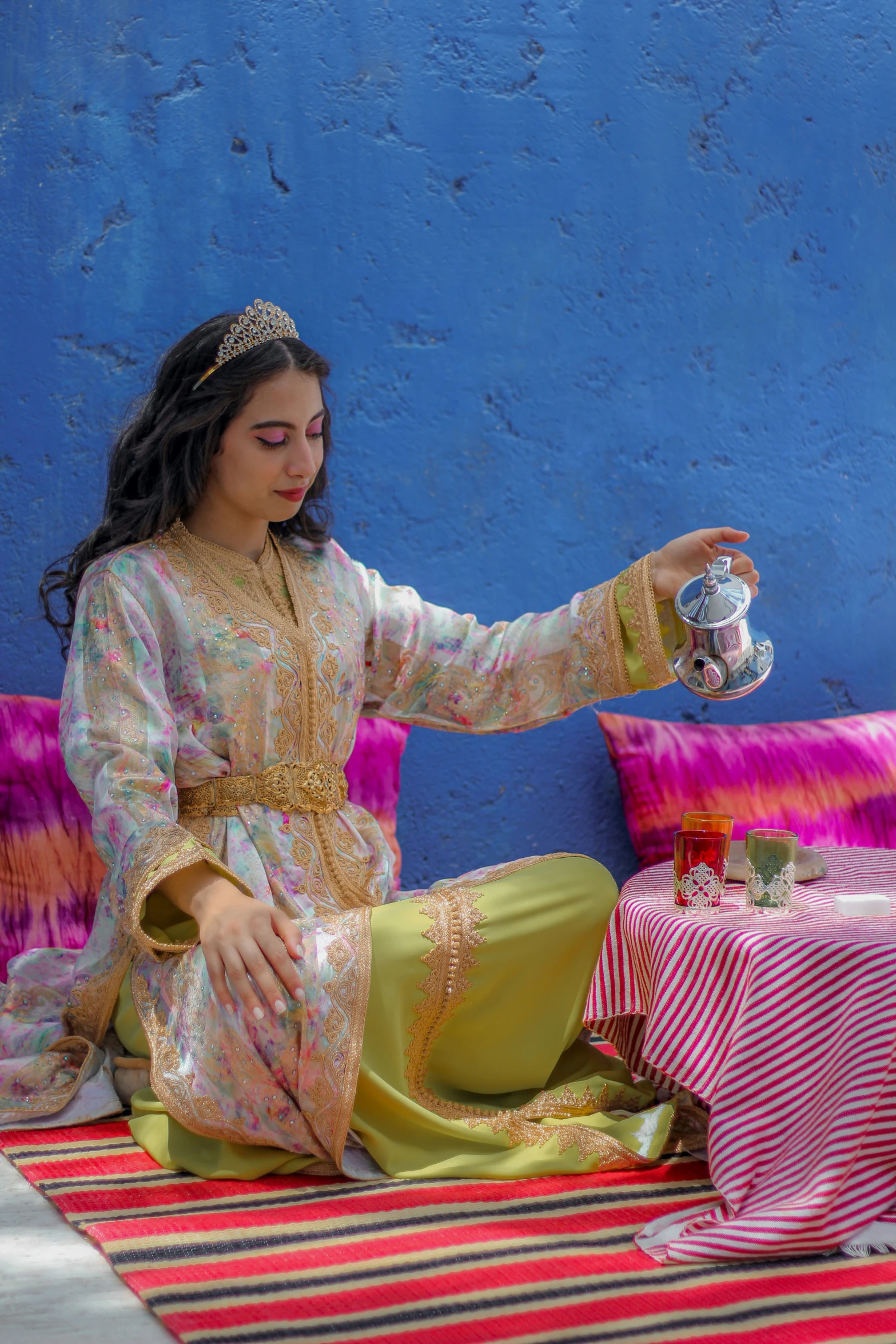 a girl sitting down and holding a tea pot