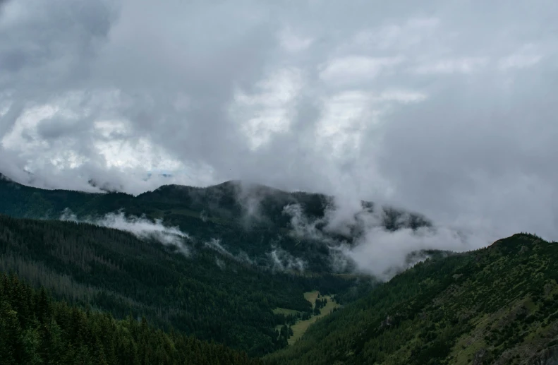 a very cloudy mountain range with a valley in the distance