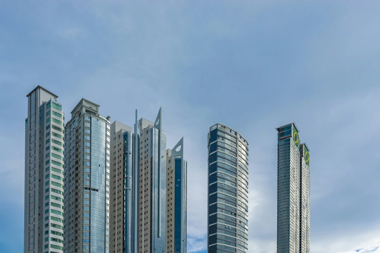 several tall buildings stand in front of a cloudy blue sky