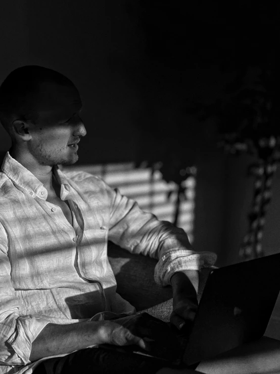 man sitting down working on a laptop in a chair