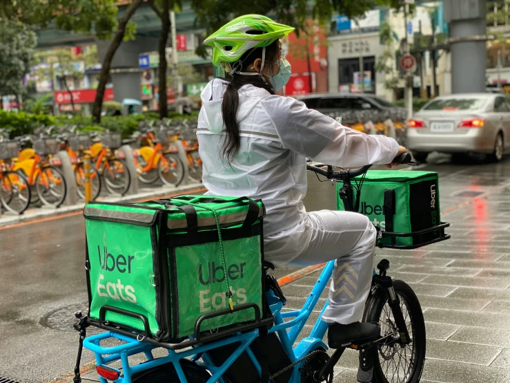 the woman is riding her bike with two boxes on the back