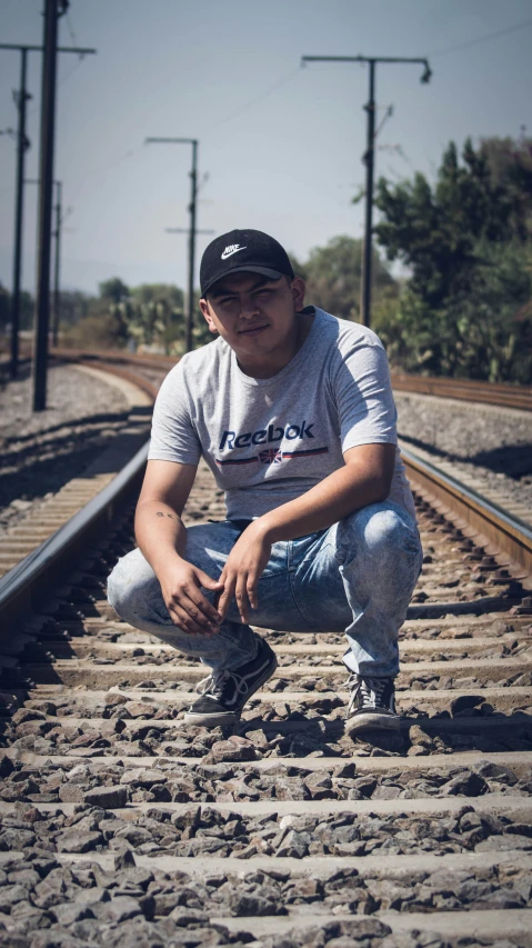 a man squatting down by some railroad tracks
