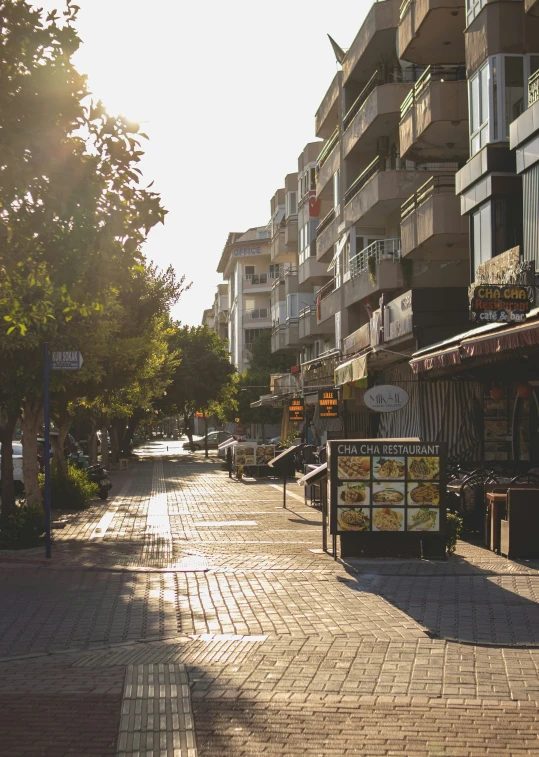 the sun is shining on a side street near tall buildings