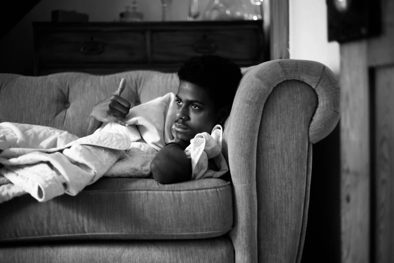 a person laying on a couch holding a drink and reading