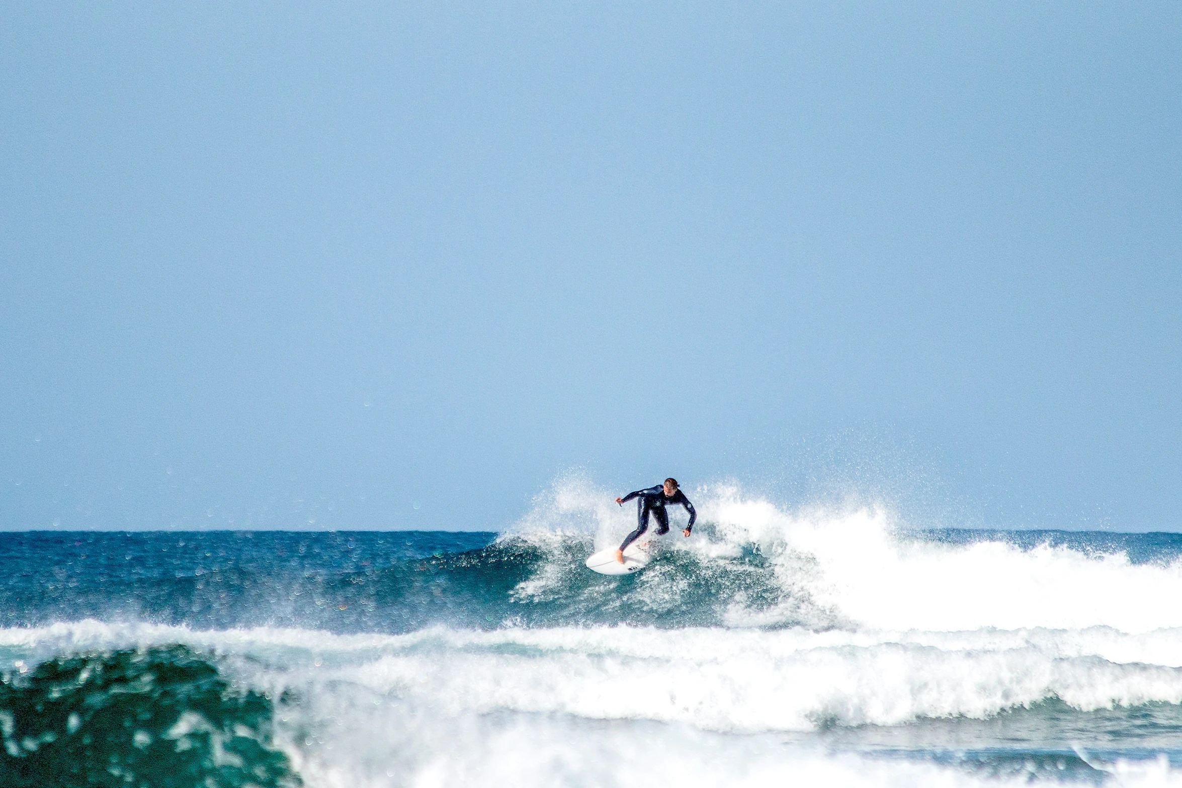 surfer riding wave in open ocean with sky