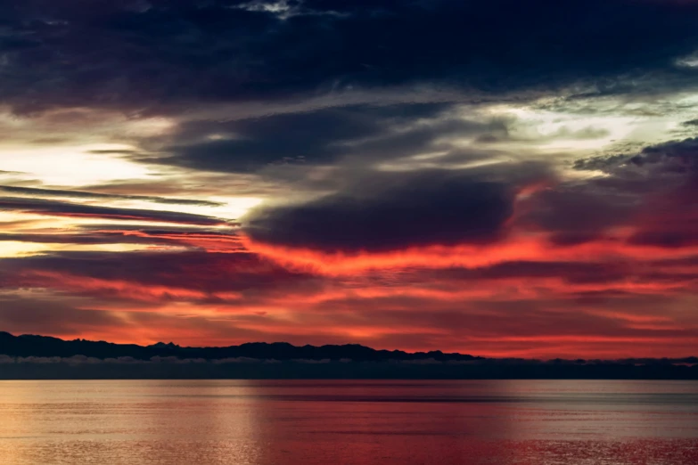 a sunset over the water with red clouds