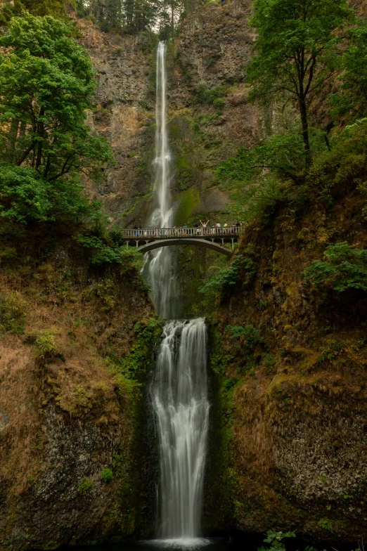 waterfall in the middle of a lake and wooden bridge