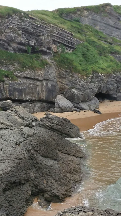 a sandy shore with lots of rock formations next to the ocean