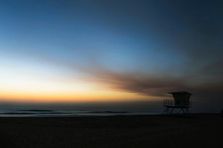 an empty lifeguard stand on the beach in front of a blue sky