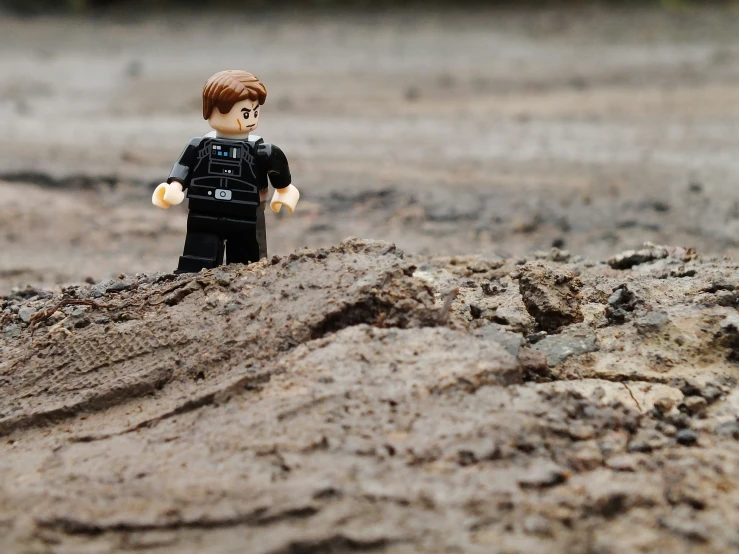 a toy person is standing in a sandy area