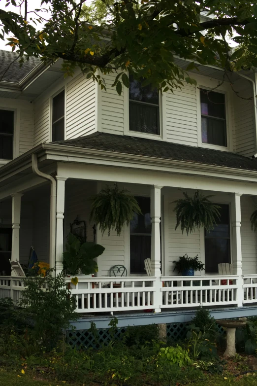 a white two story house sitting next to a lush green hillside