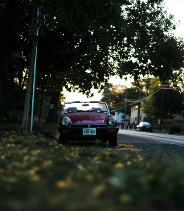 a car parked in front of trees on a street