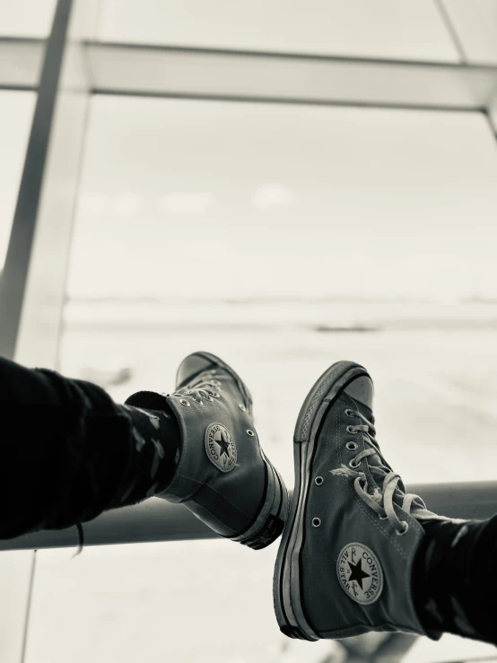 two feet with shoes in front of an airport window